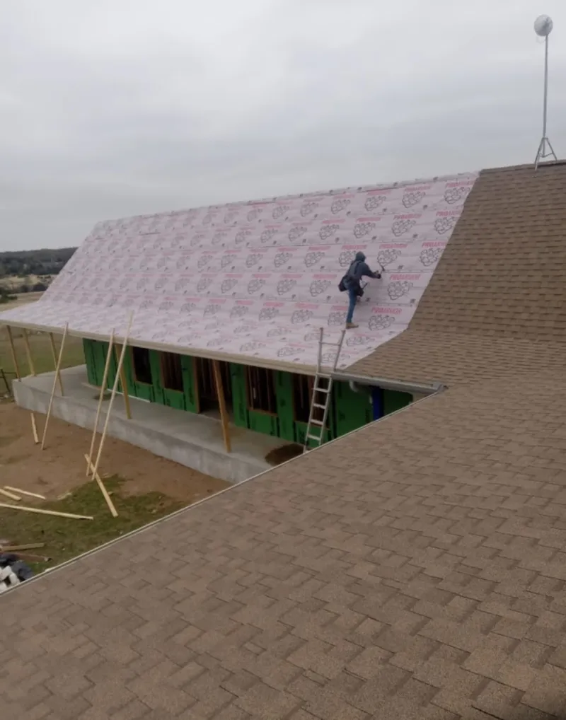 Worker preparing underlayment for a metal roof installation in Clemson
